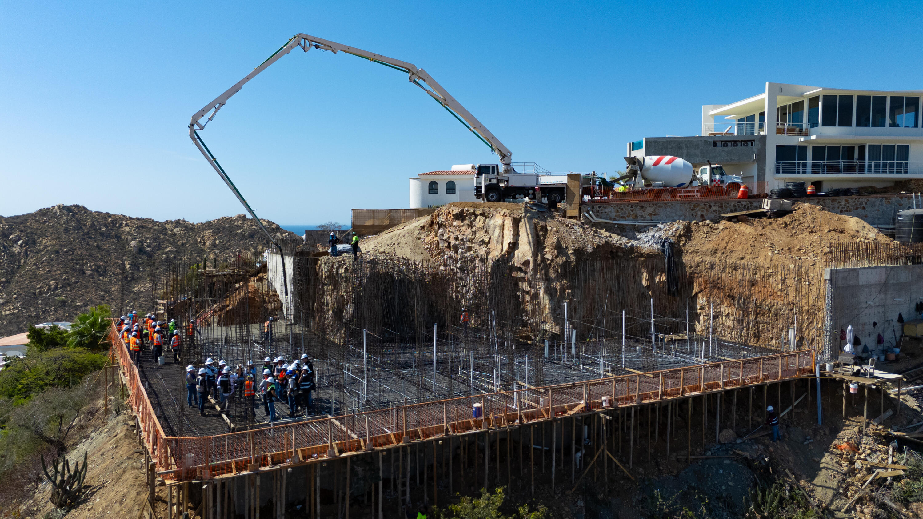 Rebar grid, crew, and concrete pump on the Villa del León slab in Pedregal, Cabo